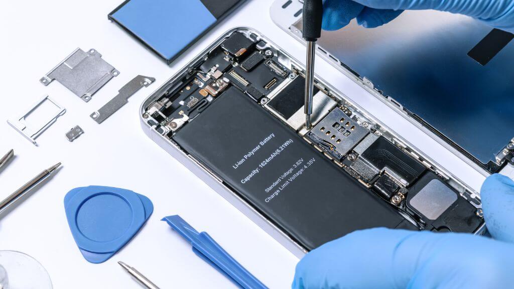 Person wearing blue gloves repairing a smartphone