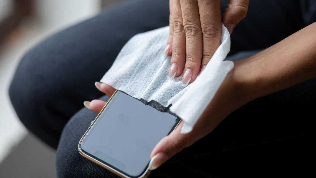 A person cleaning a smartphone screen with a white cloth